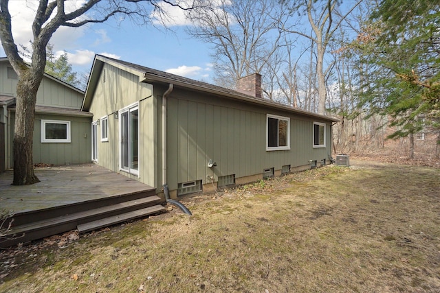 back of house with a wooden deck, cooling unit, and a chimney