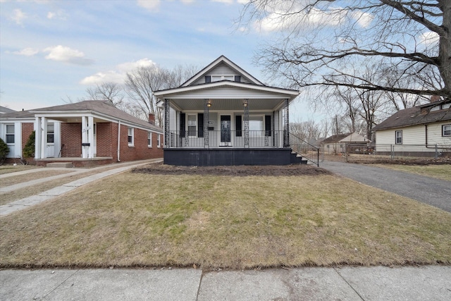 view of front facade with aphalt driveway, brick siding, covered porch, and a front yard