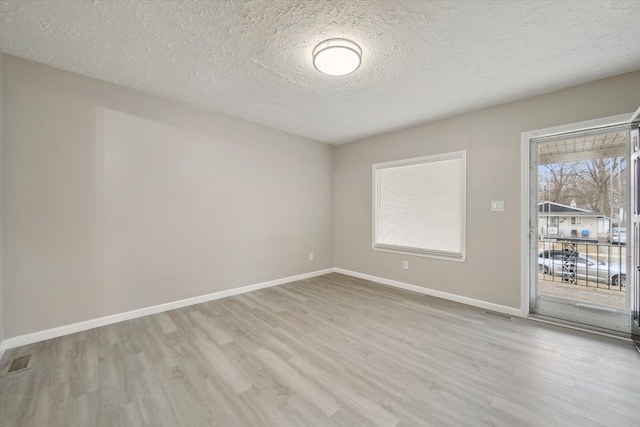 spare room with visible vents, baseboards, a textured ceiling, and wood finished floors