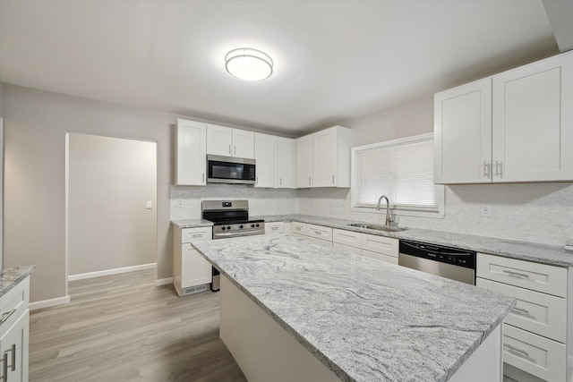 kitchen featuring decorative backsplash, light wood-style flooring, appliances with stainless steel finishes, white cabinets, and a sink