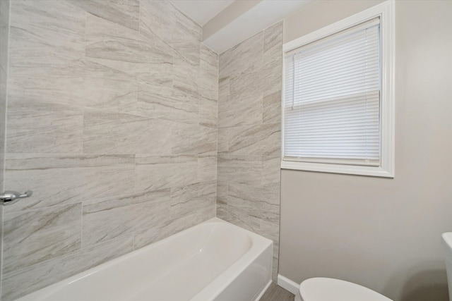 bathroom with toilet, baseboards, and a wealth of natural light