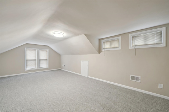 additional living space with visible vents, baseboards, carpet, and vaulted ceiling