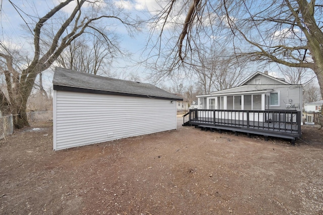 exterior space with an outbuilding, a wooden deck, fence, and dirt driveway