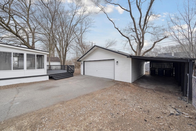 view of side of home featuring a garage, a carport, an outdoor structure, and a sunroom