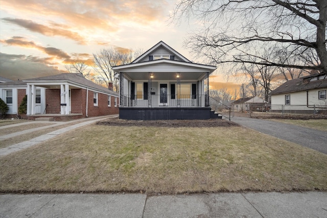 view of front of house with a porch, a front lawn, and driveway