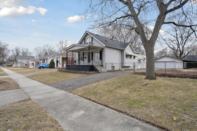 view of front of home featuring fence, covered porch, a chimney, a front lawn, and a garage