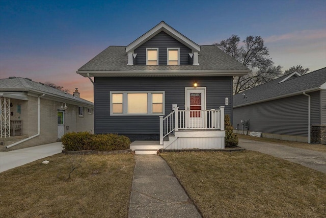 bungalow-style home featuring a yard and roof with shingles