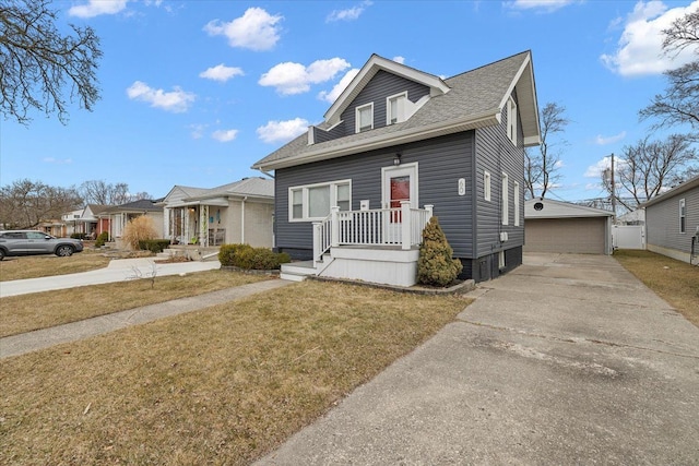 view of front of home featuring an outbuilding, a shingled roof, a detached garage, and a front yard