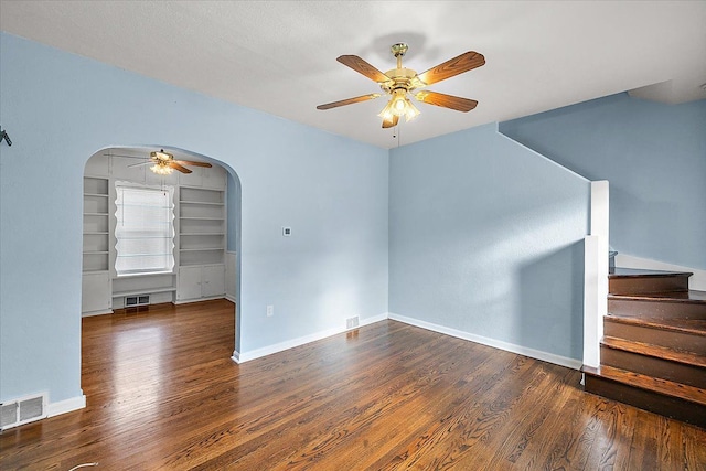 spare room featuring visible vents, arched walkways, wood finished floors, and stairs