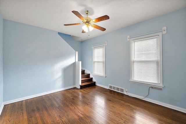 spare room with visible vents, stairs, baseboards, and hardwood / wood-style floors