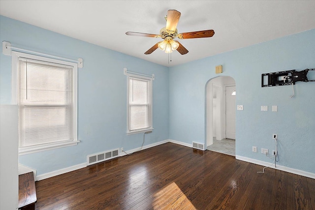 spare room with visible vents, arched walkways, and wood finished floors