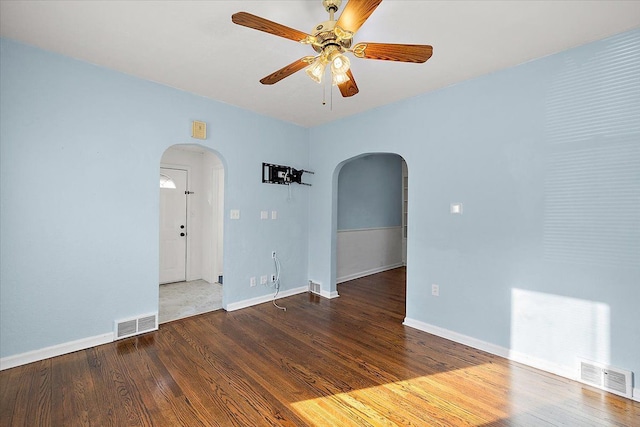 spare room with visible vents, arched walkways, baseboards, and wood finished floors