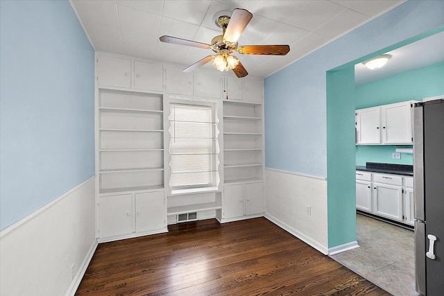 unfurnished dining area with a ceiling fan, wood finished floors, visible vents, and baseboards