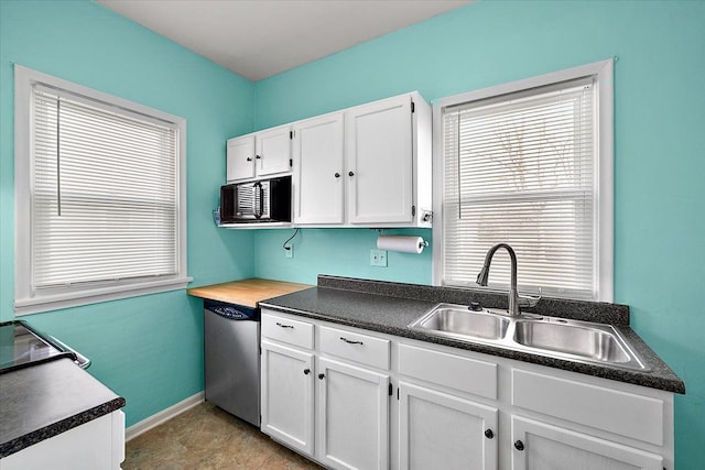 kitchen with dark countertops, baseboards, dishwasher, white cabinetry, and a sink