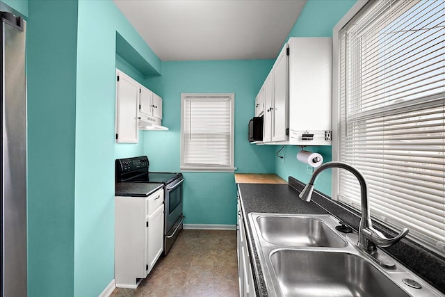 kitchen with a sink, white cabinets, under cabinet range hood, range with electric stovetop, and dark countertops