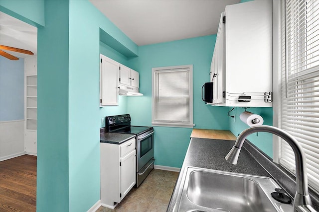 kitchen featuring a sink, range with electric cooktop, under cabinet range hood, white cabinetry, and dark countertops