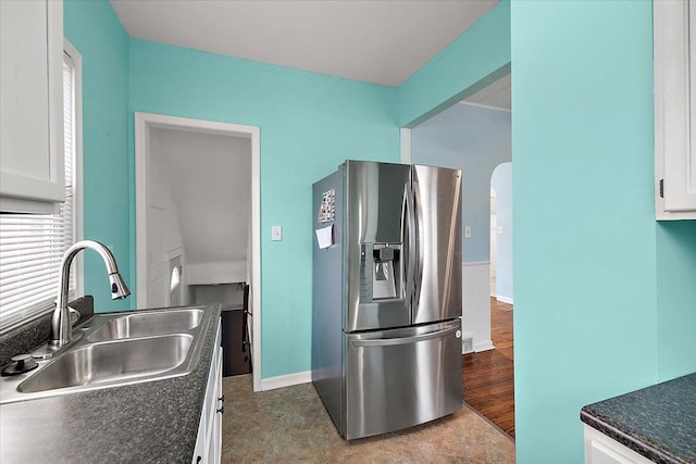 kitchen featuring white cabinets, arched walkways, stainless steel refrigerator with ice dispenser, and a sink