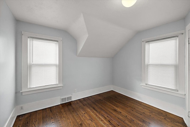 bonus room featuring visible vents, lofted ceiling, baseboards, and dark wood-style flooring