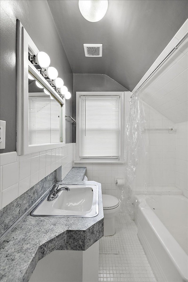 bathroom with visible vents, tile patterned flooring, vaulted ceiling, tile walls, and toilet