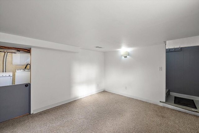 finished basement with baseboards, visible vents, and washing machine and clothes dryer