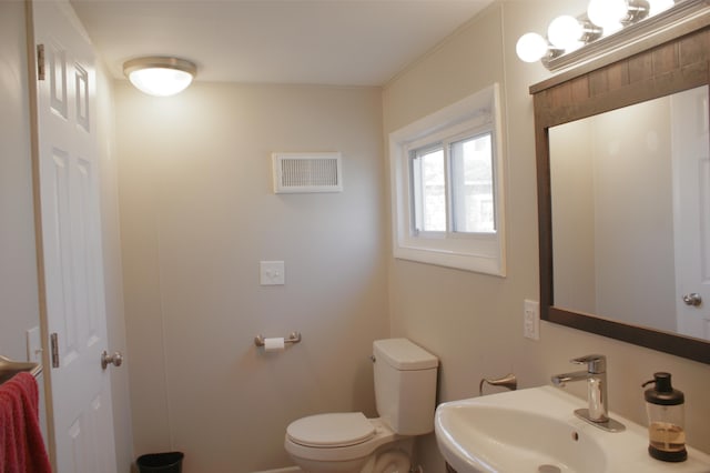 bathroom with toilet, visible vents, and a sink