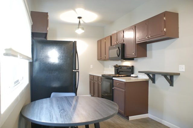 kitchen featuring baseboards, light wood-style floors, black appliances, and light countertops