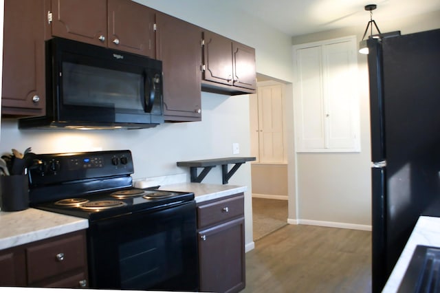 kitchen with dark brown cabinets, baseboards, black appliances, and wood finished floors