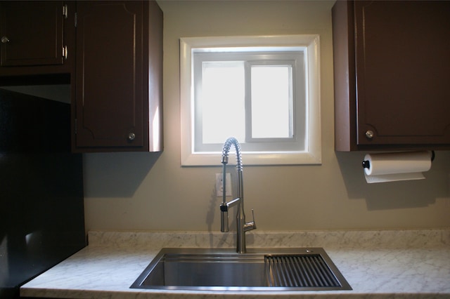 kitchen with dark brown cabinetry, light countertops, and a sink