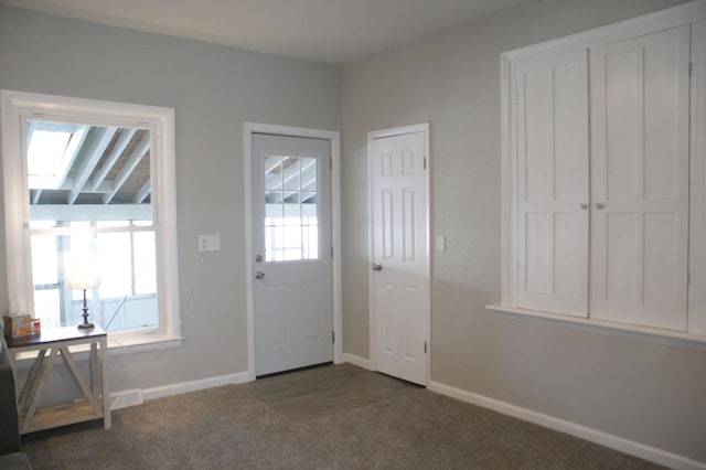 entryway with dark carpet and baseboards