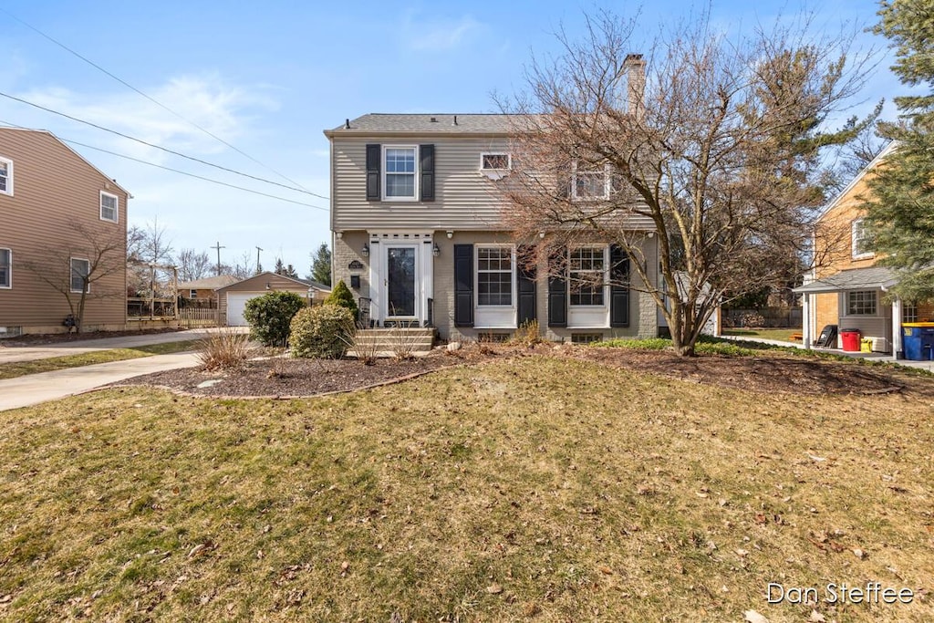 colonial inspired home featuring a chimney and a front lawn