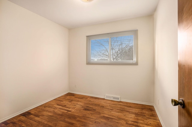 spare room featuring visible vents, baseboards, and wood finished floors