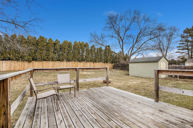 wooden terrace with a storage unit, an outbuilding, a fenced backyard, and a lawn