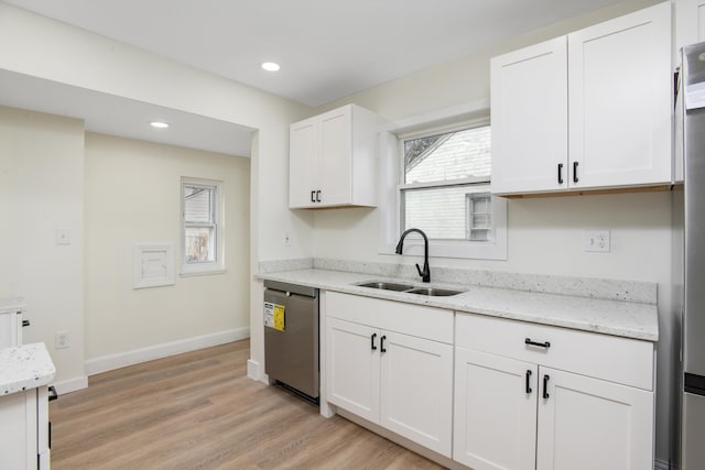 kitchen featuring baseboards, dishwasher, light wood-style flooring, white cabinetry, and a sink