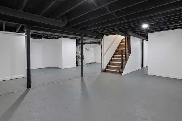 finished basement with stairway, baseboards, and heating unit