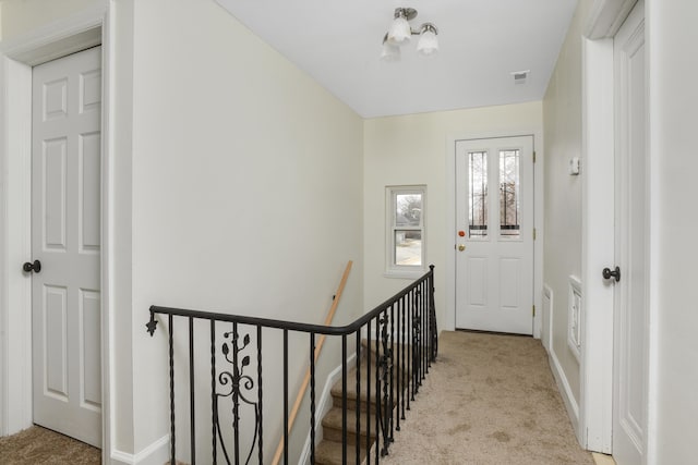 interior space with an upstairs landing, carpet flooring, baseboards, and visible vents