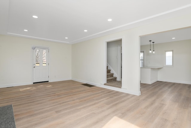 unfurnished living room featuring recessed lighting, stairway, and light wood-style flooring