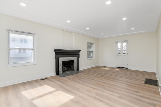 unfurnished living room featuring light wood-style flooring, a fireplace with flush hearth, recessed lighting, and visible vents