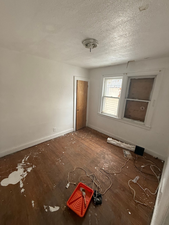 unfurnished room with baseboards and a textured ceiling