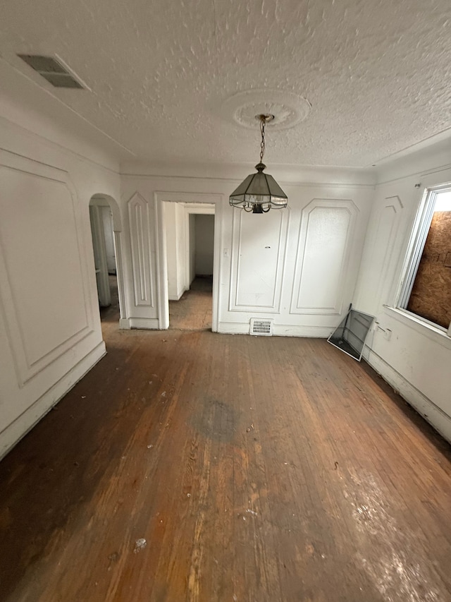 interior space featuring arched walkways, visible vents, a textured ceiling, and wood-type flooring