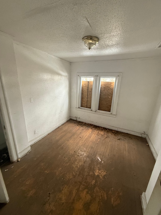 spare room with a textured ceiling and hardwood / wood-style floors