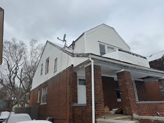 view of side of property with brick siding and fence