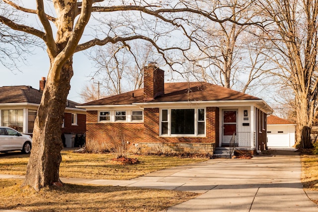 view of front of house with an outbuilding, a garage, brick siding, and a chimney