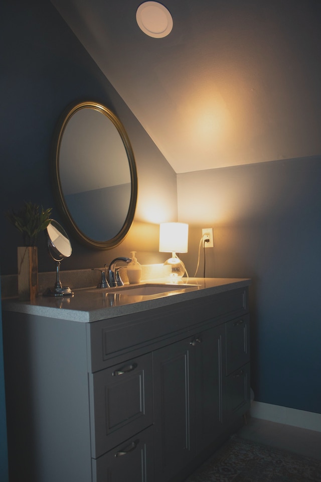 bathroom with vanity, baseboards, and vaulted ceiling