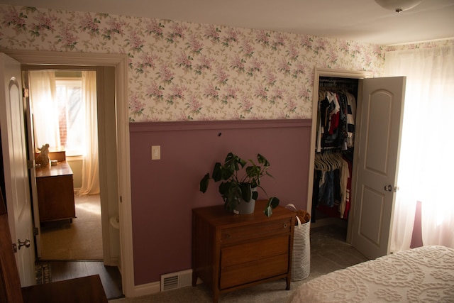 bedroom featuring a closet, visible vents, wainscoting, and wallpapered walls