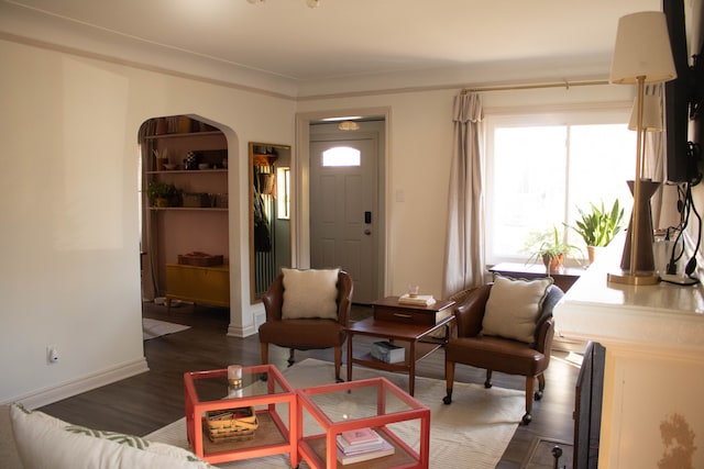 living area with baseboards, arched walkways, and dark wood finished floors