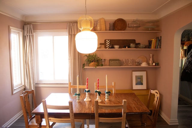 dining space featuring arched walkways, wood finished floors, baseboards, and built in shelves