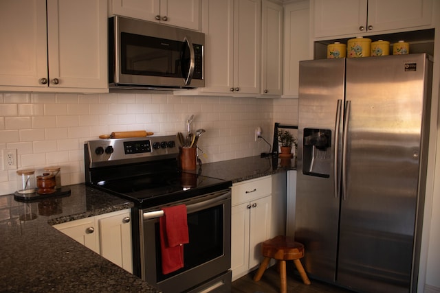 kitchen featuring decorative backsplash, white cabinets, stainless steel appliances, and dark stone countertops