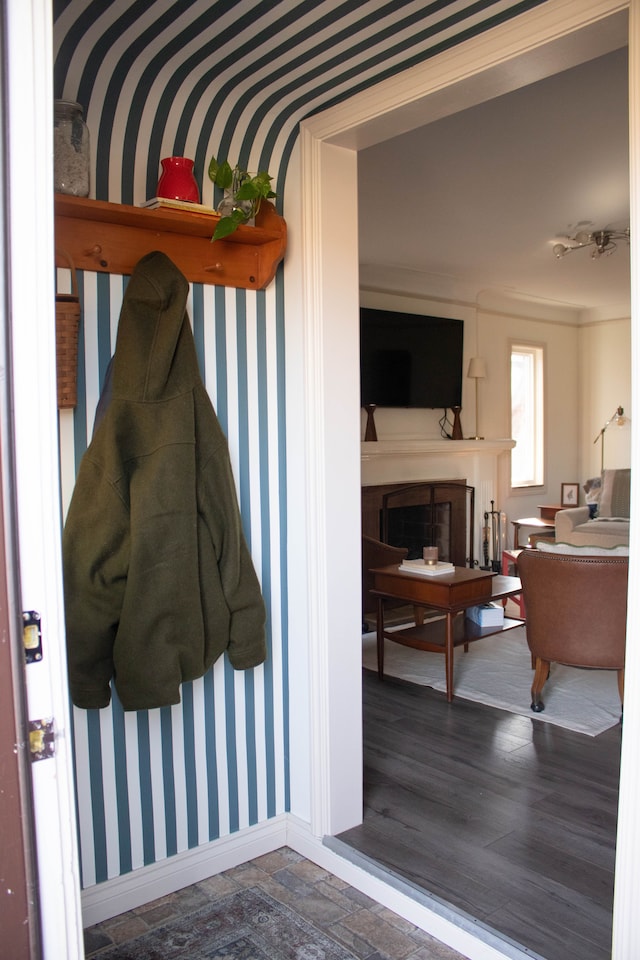 mudroom featuring wallpapered walls, a fireplace, baseboards, and stone finish flooring