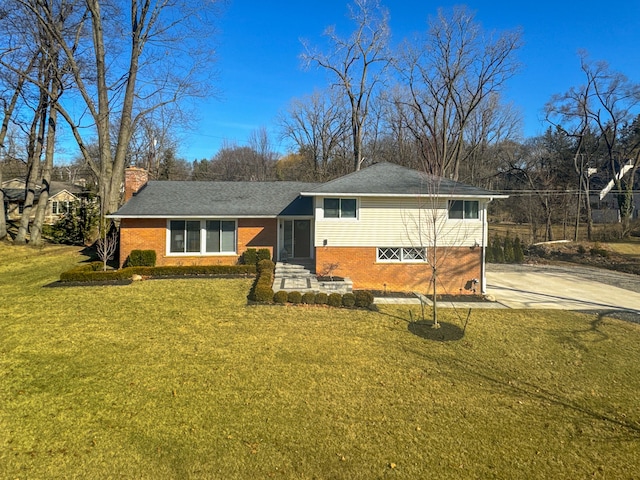 split level home featuring brick siding, concrete driveway, a chimney, and a front lawn