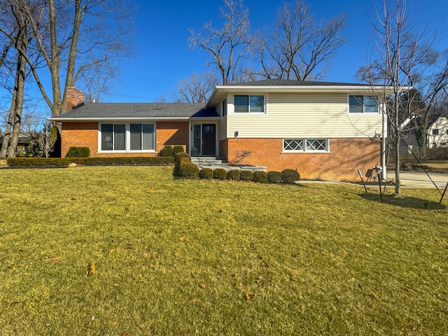 split level home featuring brick siding, a chimney, and a front yard